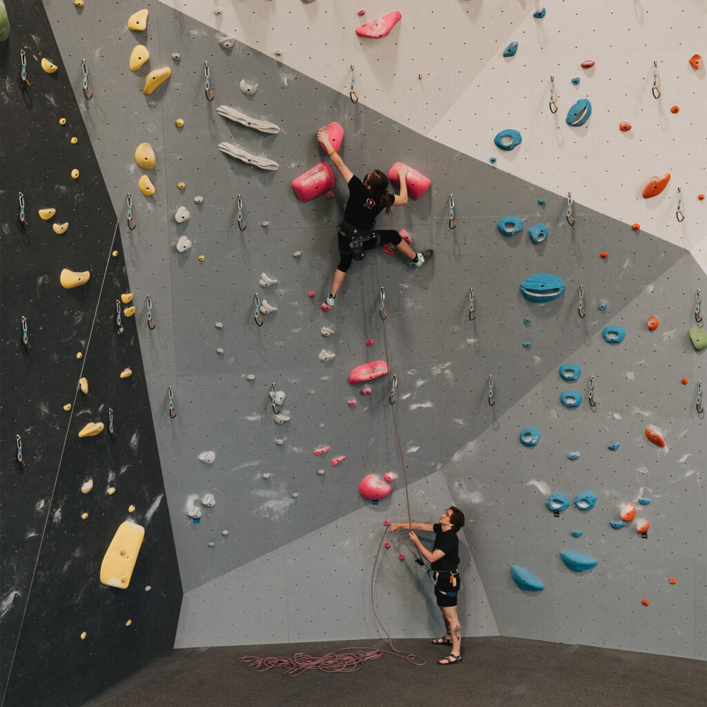 A young climber on a rope with a belayer.