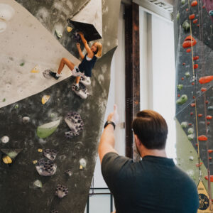 Generic white man gives thumbs up to a climber on a bouldering wall in St. Louis, MO.